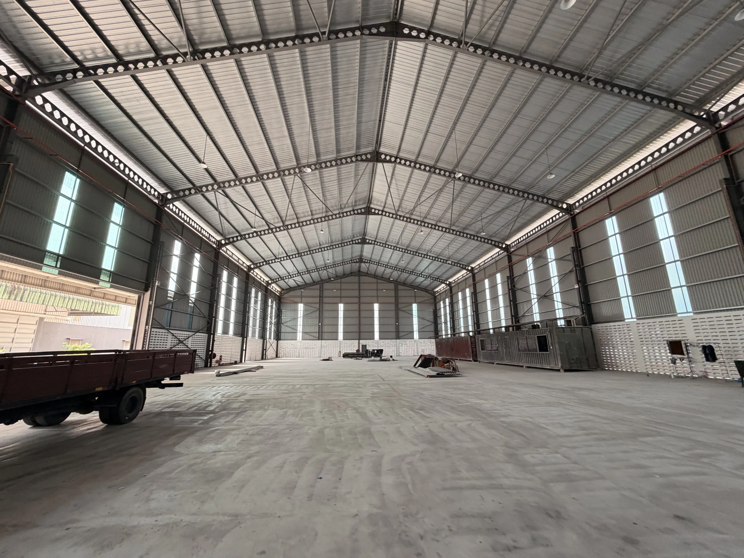 Inside a clear-span steel portal-frame factory, looking down the full length of the floor