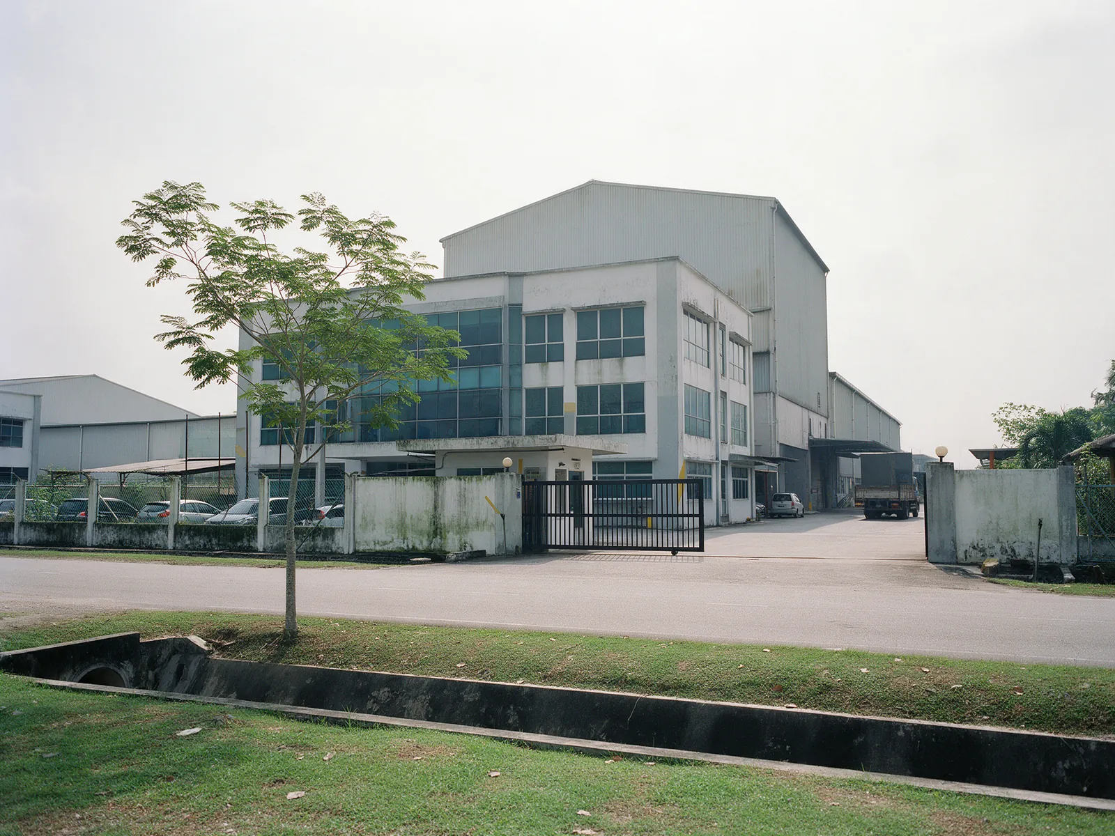 Illustration: a detached factory with a glazed office block and gated compound