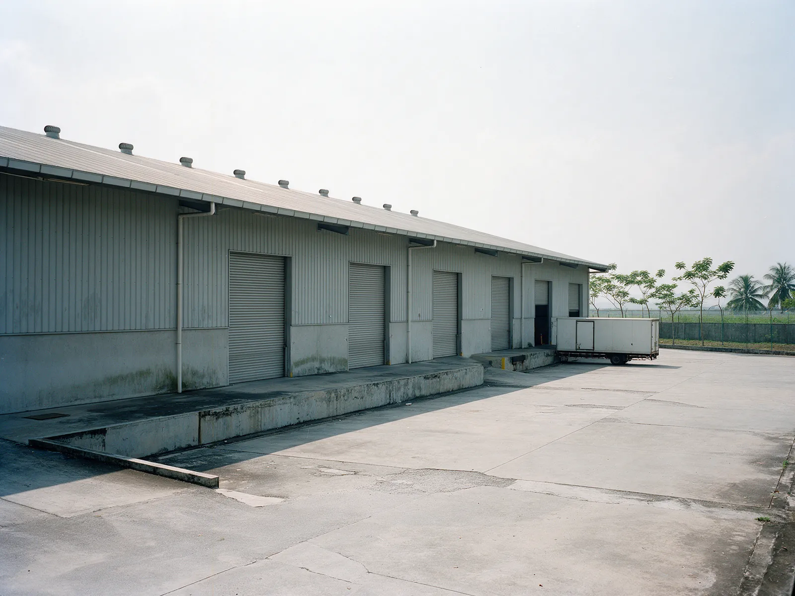 Illustration: a detached warehouse with roller shutter loading doors along its long side
